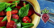 Image of carrot and beetroot icons falling over bowl of fruit salad on blue wooden table