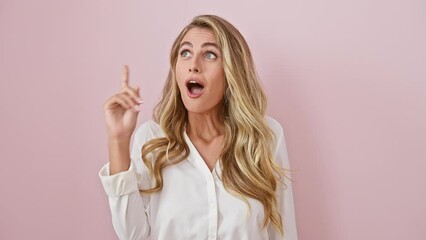 Canvas Print - Excited young blonde woman, standing in a shirt over an isolated pink background, points her finger up with a happy expression, celebrating her number one success idea!