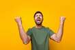 Photo portrait of attractive young man raise fists celebrate win lottery wear trendy khaki clothes isolated on yellow color background