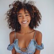 Beautiful black woman with curly hair, happy and smiling while touching her face against a white background. She is wearing . Young, trendy model posing for a beauty concept