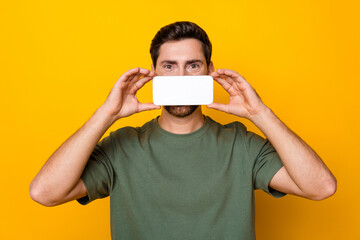 Poster - Photo portrait of attractive young man cover mouth hold device white screen wear trendy khaki clothes isolated on yellow color background