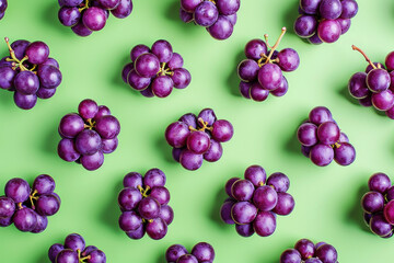 Wall Mural - Top view of ripe purple grapes on a vibrant green background, fresh fruit arrangement flat lay concept