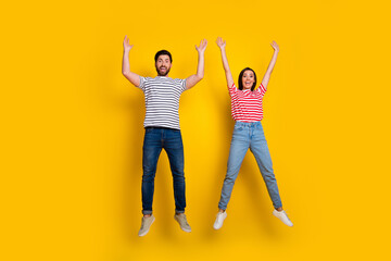 Wall Mural - Full length photo of funky cute couple wear striped t-shirt raising hands up announcing sale isolated on vivid yellow color background