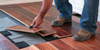  person installing wood flooring in an empty room,a close up of a man laying a wooden floor on a hard wood floor depicts a man installing wooden flooring. home renovation, construction,new floor insta
