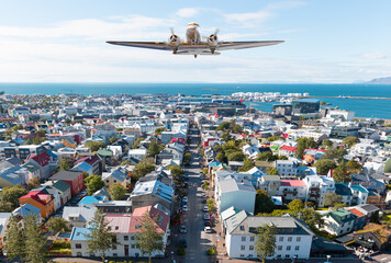 Wall Mural - Aerial view of colorful buildings in Reykjavik Iceland - Vintage type old metallic propeller airplane taking off from the airport