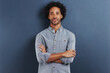 © Katie/peopleimages.com - Happy man, portrait and arms crossed in studio as professional, confident and fashion by blue background. African person, face and smile for ambition as designer and creativity or pride in mock up
