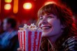 Woman enjoying popcorn at the theater, a wide grin on their face as they watch a comedy unfold on screen