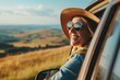 © Maelgoa - A woman traveler smiling as they hit the road for a vacation by car, passing through a scenic countryside landscape with rolling hills and green fields