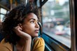 Black woman with a contemplative gaze staring out the window of the bus, lost in thought as she reflects on past travels and looks forward to the adventures that lie ahead