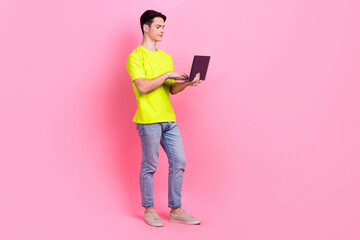 Sticker - Full length photo of positive dreamy guy wear green t-shirt communicating modern gadget empty space isolated pink color background