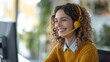 © Marta B - Young woman wearing a yellow cardigan and a white shirt, with curly hair, smiling and wearing a headset, representing a customer service representative or a call center operator.