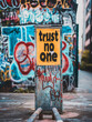 Graffiti-covered sign with phrase trust no one in urban setting