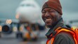 African American airport worker smiling. Airport operator, baggage handler or aircraft mechanic on the tarmac of an airport
