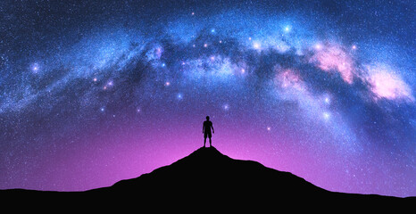 Wall Mural - milky way arch and man on the mountain peak at starry night. silhouette of alone guy, pink sky with 