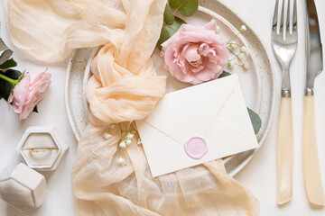 Wall Mural - Envelope near cream fabric knot and light pink roses on plates top view copy space, wedding mockup