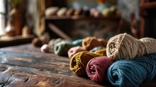 A Wooden Table With Several Rolls Of Yarn In Different Colors And Textures.