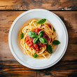 Plate of spaghetti or pasta with tomato sauce and basil leaves on a wooden table