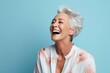 Cheerful senior woman. Portrait of beautiful mature woman laughing while standing against blue background