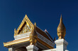 Detailed golden decorations at Wat Traimit (Temple of the Golden Buddha) in Bangkok, Thailand. Blue sky in the background. 
