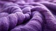 Close-up of a purple knitted fabric showing detailed texture, interwoven fibers, and cozy, soft appearance