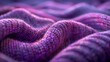 Image shows a close-up of textured fabric with a purple hue and intricate woven details