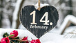 Valentinstag im Schnee: Herz aus Holz mit dem Datum 14. Februar und roten Rosen.
