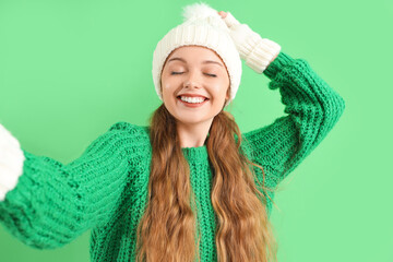 Sticker - Beautiful happy young woman in warm clothes taking selfie on green background