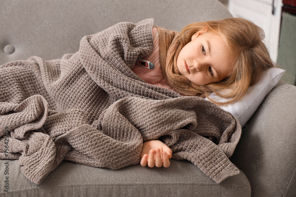 Sick little girl with plaid measuring temperature on sofa at home