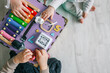 © shine.graphics - Children playing together in the nursery, handmade busy board, top view