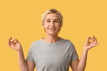 Sticker - Portrait of meditating mature woman on yellow background