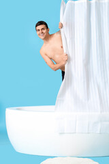 Canvas Print - Young man in bathtub with curtain on blue background