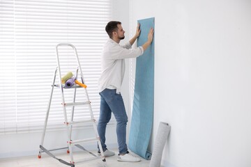 Poster - Man hanging light blue wallpaper in room