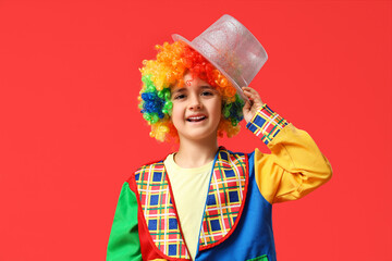 Poster - Funny little boy in clown costume with hat on red background. April Fools Day celebration