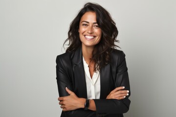 Poster - Portrait of a smiling businesswoman with arms crossed against grey background