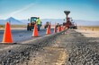 Team of road construction workers repairing a highway, with orange cones and heavy equipment lining the roadway under a clear sky, Generative AI