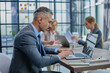 © Katsiaryna - Confident businessman sitting at conference table in modern office