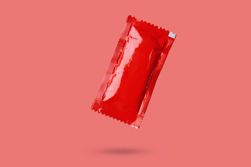 Wall Mural - Blank red foil tomato ketchup sauce sachet package float on red background