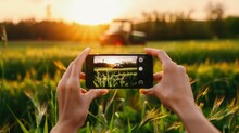 A farmer takes a photo of a working tractor on his field with a smartphone. Amidst the vast expanse of the field, the farmer captures a snapshot of his tractor's strength.