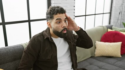 Canvas Print - Shocked young man at home, with surprised face expressing wide-eyed fear, and excited disbelief.