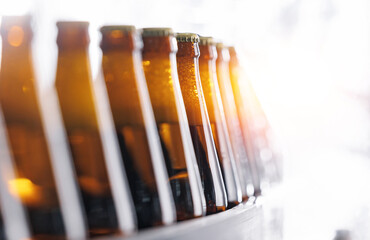 Wall Mural - Brown glass beer bottles on conveyor belt Automated brewery industry manufacturing with sunlight