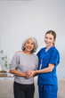 © NanSan - Caucasian female doctor assists in supporting an elderly Asian patient while they both sit on the sofa, ensuring comfort and stability during the interaction.