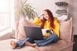 Relaxing young woman using laptop in living room