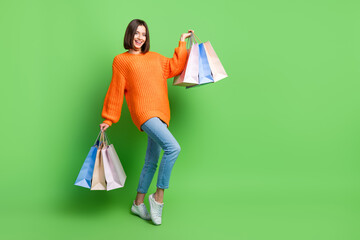 Wall Mural - full size portrait of pretty positive girl hold store mall bags empty space ad isolated on green col