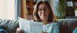 Joyful mature woman reading a document at home, expressing gratification.