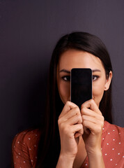 Poster - Portrait, phone screen and woman hiding on mockup space in studio isolated on a gray background. Face, display and person cover with smartphone for advertising, marketing or promo on social media app