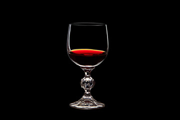 Red grape wine in a glass. On a black background. Glass crystal goblets. Pouring from a bottle. Place for text.