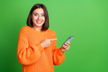 Wall Mural - Portrait of cheerful charming person toothy smile indicate finger hand hold smart phone empty space isolated on green color background