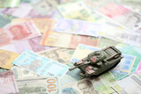 Fototapeta  - Small green tank on many banknotes of different currency. Background of war funding or spend money to defense close up