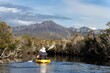 kayaking up  a river in a canoe with mountains in a wilderness in a national park with native plants and trees in a rainforest in Australia. with rivers and exploring  in australia