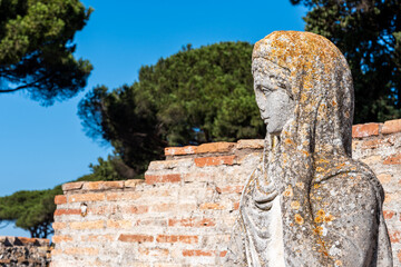 Wall Mural - Close-up on profile of ancient roman statue in ruins portraiting a young woman wearing a veil